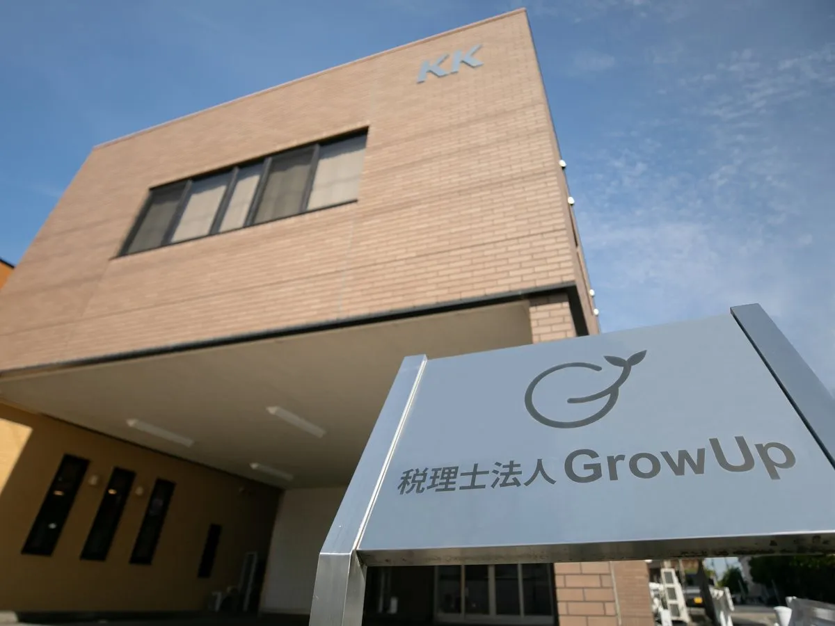 税理士法人GrowUpの外観。入口前に自社ロゴ入りの銀色の看板